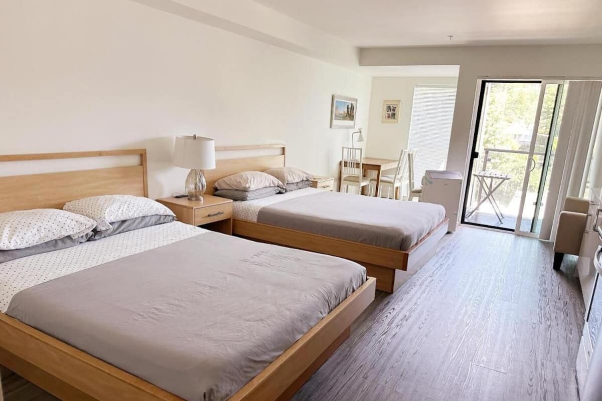 A hotel room with two wooden beds, a desk, and a chair.