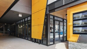A modern building entrance with glass doors, a yellow awning, and a stone facade. - Modern Studio Steps to UW (Seattle)