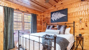 A wooden cabin bedroom with a bed, curtains, a fern artwork, and a window. - Check out Mossy Fern!! A Cozy Cabin in the Woods in Townsend, TN. (Townsend)