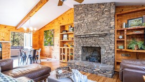 A cozy cabin interior with a stone fireplace, wooden walls, and a dining area. - Check out Mossy Fern!! A Cozy Cabin in the Woods in Townsend, TN. (Townsend)