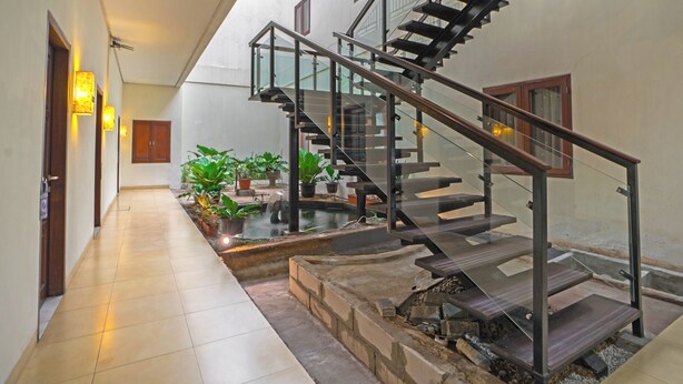 A modern interior with a staircase, potted plants, and a tiled floor. - Jambuluwuk Mansion Pakubuwono (Jakarta)