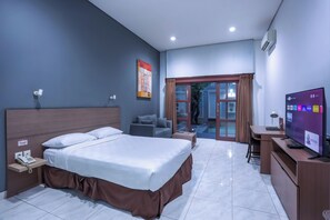 A hotel room with a bed, a desk, a TV, and a phone. - Jambuluwuk Mansion Pakubuwono (Jakarta)