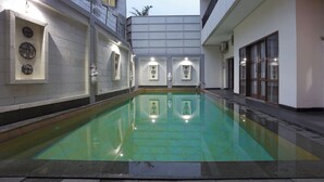 A swimming pool with tiled walls and a clear water surface, surrounded by a building with a flat roof and a balcony. - Jambuluwuk Mansion Pakubuwono (Jakarta)
