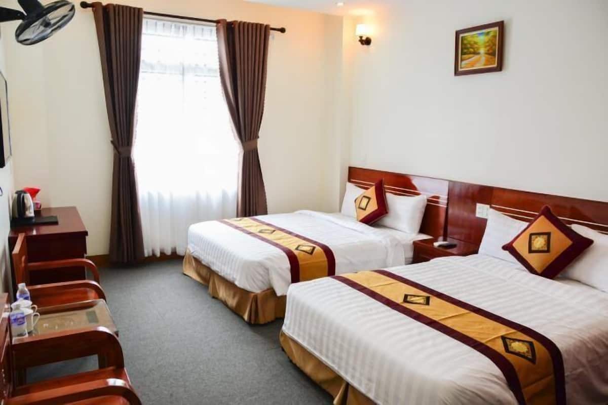 A hotel room with two beds, a desk, and a chair.