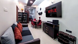 A modern living room with a sofa, TV, and a shoe rack.
