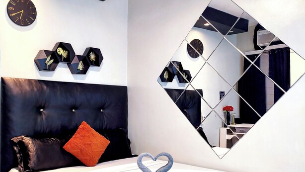 A modern bedroom with a bed, a large mirror, and a clock on the wall.