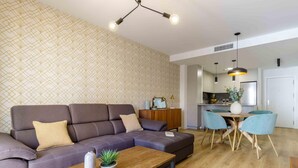Una sala de estar moderna con un sofá modular, una mesa de centro de madera y un comedor con mesa y sillas.
