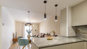 Una cocina moderna con encimera de mármol, iluminación colgante y comedor con mesa y sillas.