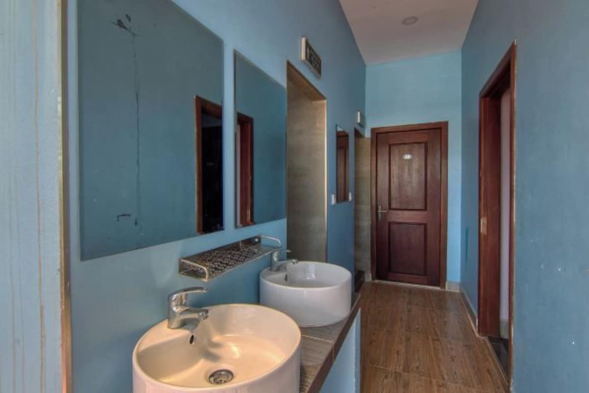 Une salle de bain avec deux lavabos, un miroir et une porte en bois.