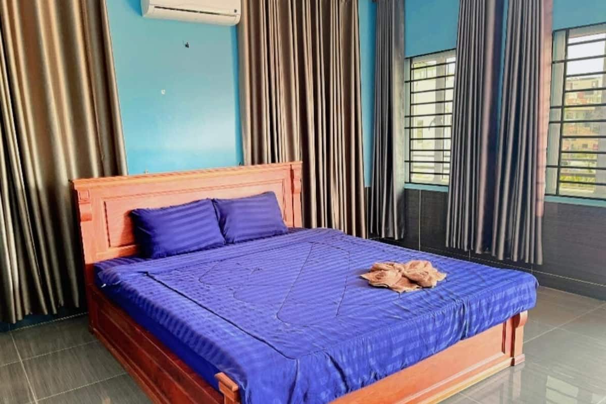 Ein Einzelbett mit Holz Kopfteil und blauer Bettdecke in einem Zimmer mit blauen Wänden und Vorhängen.