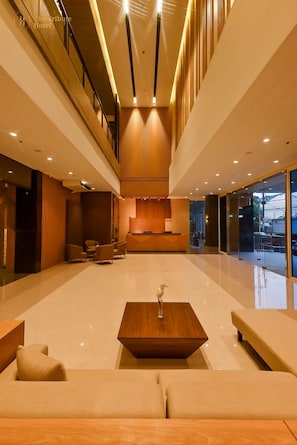 A spacious lobby with a central seating area, a reception desk, and a high ceiling with recessed lighting. - The Tribute Hotel (Quezon City)