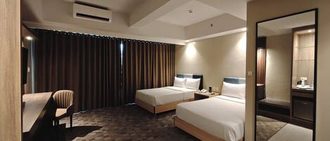 A hotel room with two beds, a desk, a chair, a large mirror, and a view of the outside through the window.