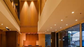 A modern reception area with a wooden reception desk, seating, and a glass wall providing a view of the outside.
