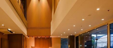 Un área de recepción moderna con un mostrador de madera, asientos y un muro de cristal que ofrece vistas al exterior.