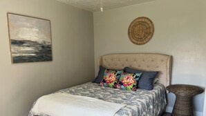 Une chambre à coucher avec un lit, un banc en bois, une tapisserie murale tissée et un tableau accroché au mur.