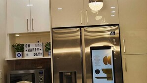 Cozinha moderna com eletrodomésticos de aço inoxidável, incluindo geladeira e micro-ondas, e iluminação pendente.