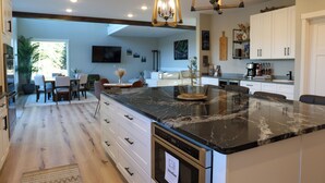 Cocina moderna con una isla grande, electrodomésticos integrados y una zona de comedor con vistas.