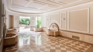 A spacious lobby with a checkered floor, a central fountain, and a view of greenery outside. - Vittorio Emanuele | Luxe Flat (Roma)