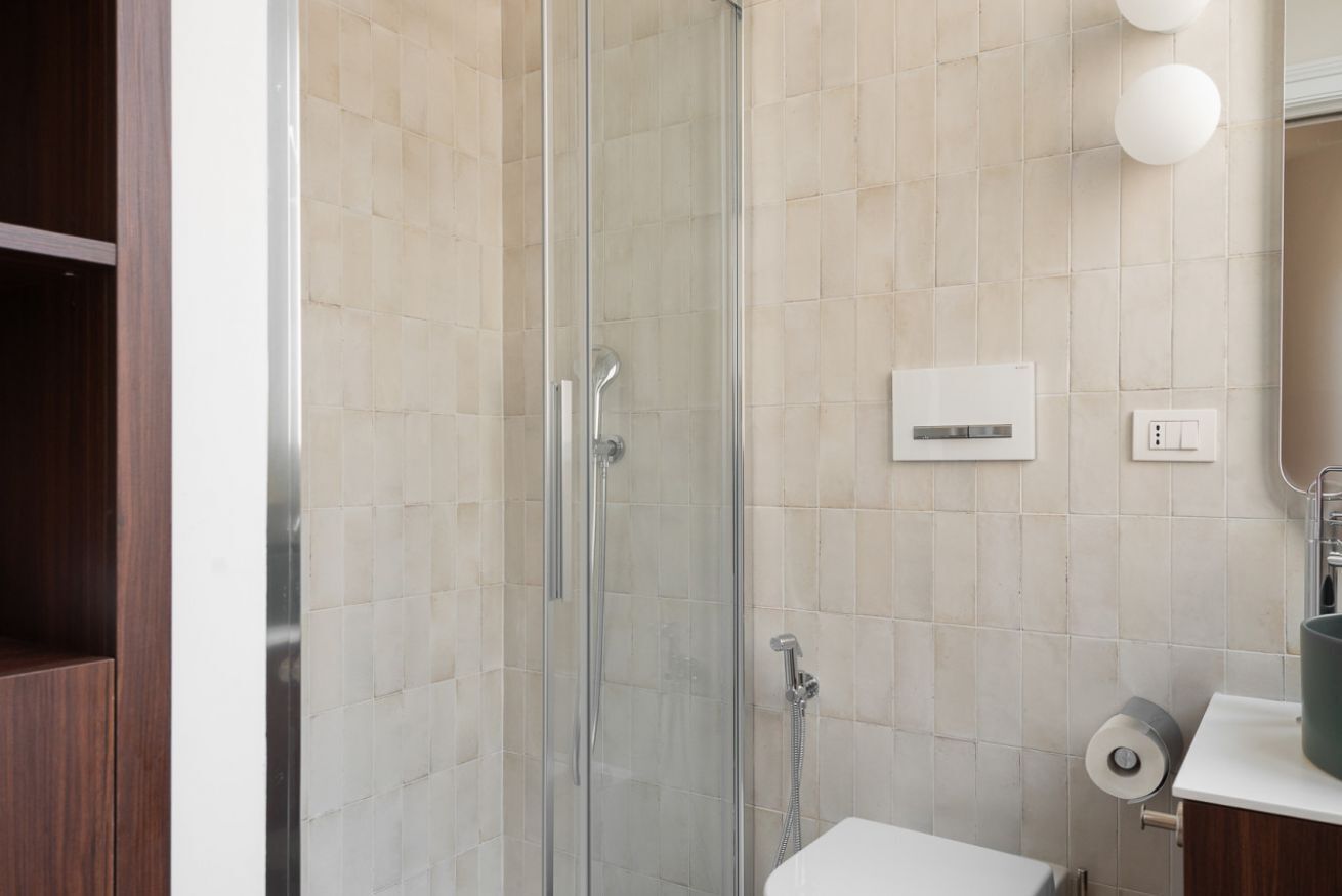 A modern bathroom with a glass-enclosed shower, a white sink, and a toilet.