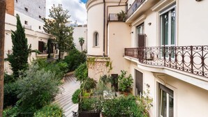 A multi-story building with balconies, a staircase, and surrounding greenery. - Vittorio Emanuele | Luxe Flat (Roma)