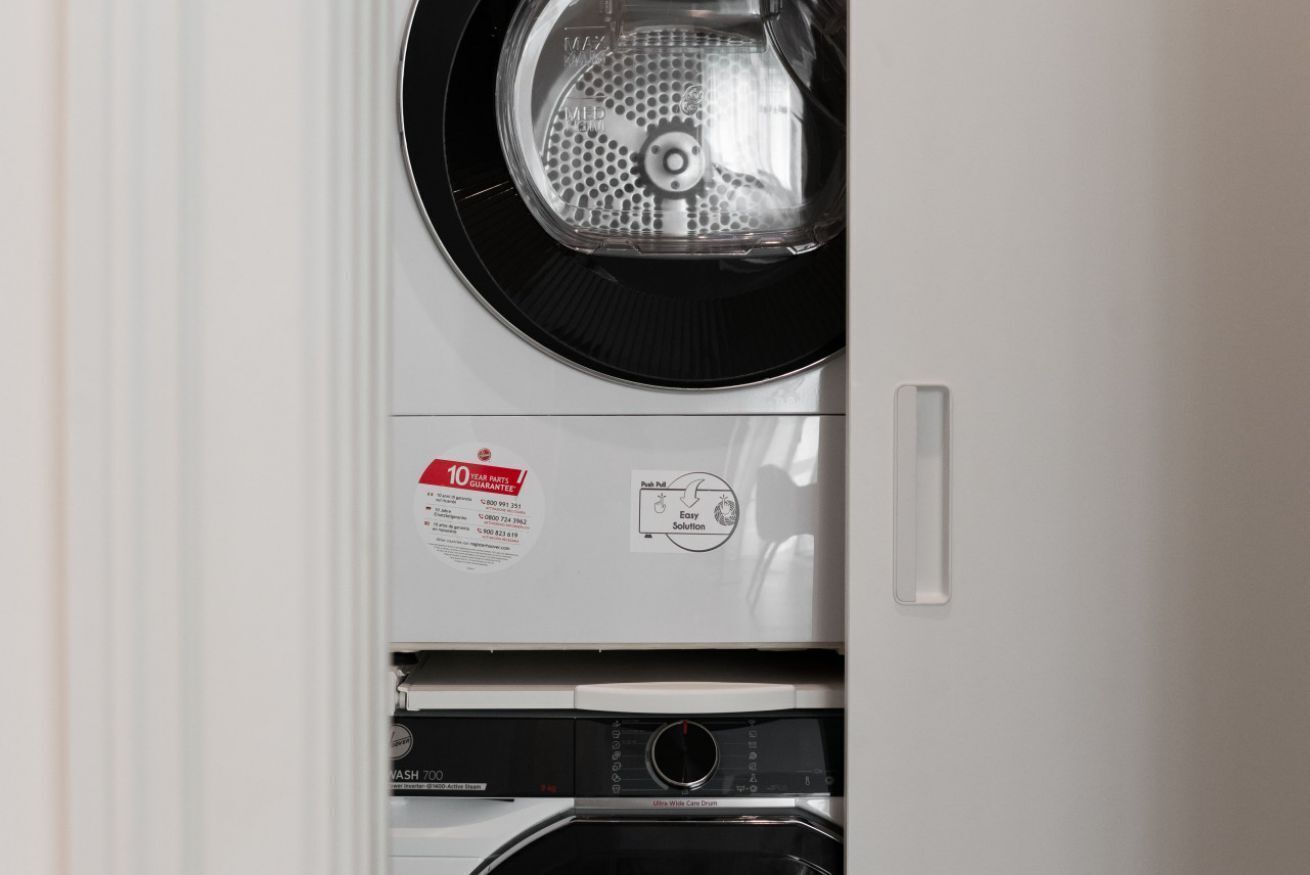 A front view of a washing machine with a control panel, a label indicating a 10-year warranty, and a push-pull door.