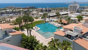 Un complexe hôtelier doté d’une piscine entourée de palmiers et offrant une vue sur l’océan.