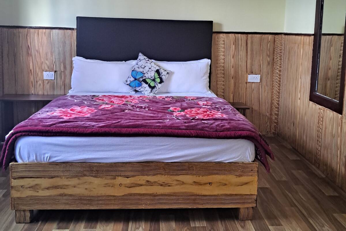 A bed with a wooden headboard, white pillows, and a floral bedspread.