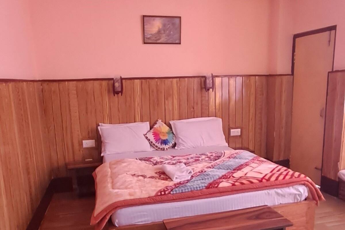 A bedroom with a wooden bed, a bench, and a wall-mounted painting.