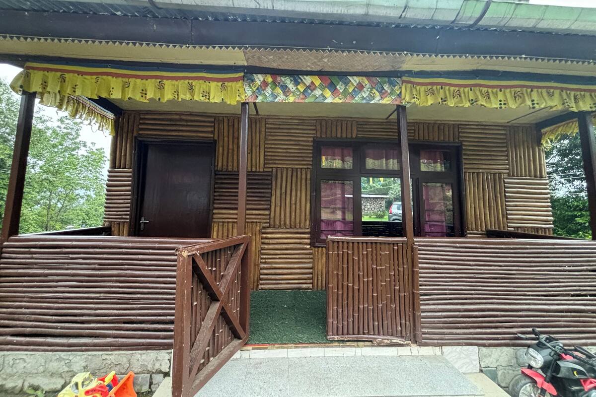 A traditional wooden structure with a covered entrance, a small porch area, and a motorcycle parked outside.