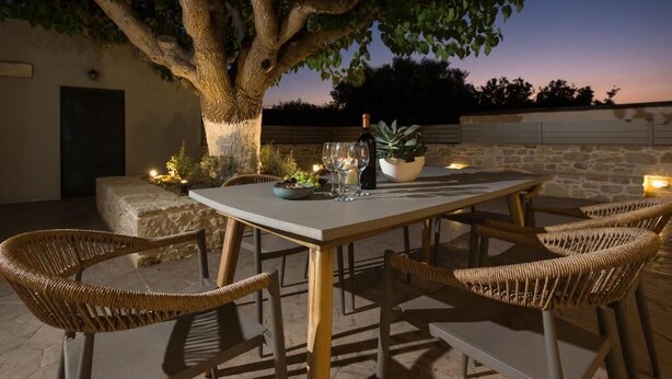 Un espace de restauration en plein air avec une table et des chaises, une bouteille de vin et une bougie.