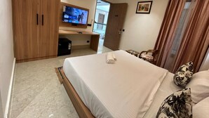 A hotel room with a bed, a desk, a TV, and a wardrobe. - Blue Moon Residency Sector 53 Gurgaon (Gurugram)