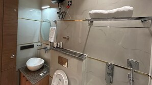 A modern bathroom with a marble wall, a white sink, a glass shower enclosure, and a towel rack. - Blue Moon Residency Sector 53 Gurgaon (Gurugram)