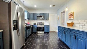 A modern kitchen with stainless steel appliances, blue cabinets, and black tiled flooring. - 3-bedroom in Mid City, walking distance to LSU lakes, Garden District (Baton Rouge)