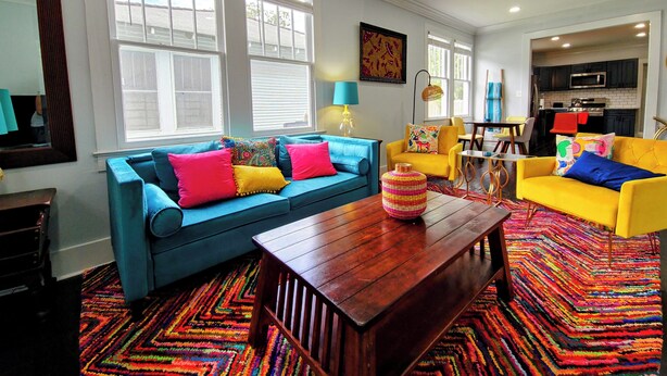 A living room with a blue sofa, yellow armchairs, and a wooden coffee table. - 3-bedroom in Mid City, walking distance to LSU lakes, Garden District (Baton Rouge)