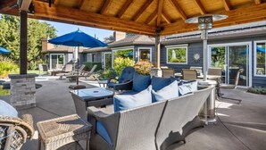 An outdoor patio with wicker furniture, a ceiling fan, and umbrellas.
