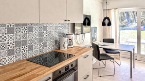 Una cocina moderna con un salpicadero decorativo, encimera de madera, horno empotrado y una zona de comedor con mesa y sillas.