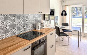 Une cuisine moderne avec un crédence à motifs, un plan de travail en bois, un four encastré et un coin repas comprenant une table et des chaises.