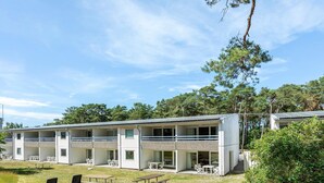 Un edificio moderno de varios pisos con mesas al aire libre y un patio cubierto.