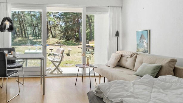 Habitación con sofá, una mesa de comedor y vista a un espacio exterior con patio.