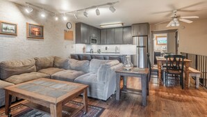 A modern living room with a sectional sofa, a coffee table, and a dining area with a table and chairs.