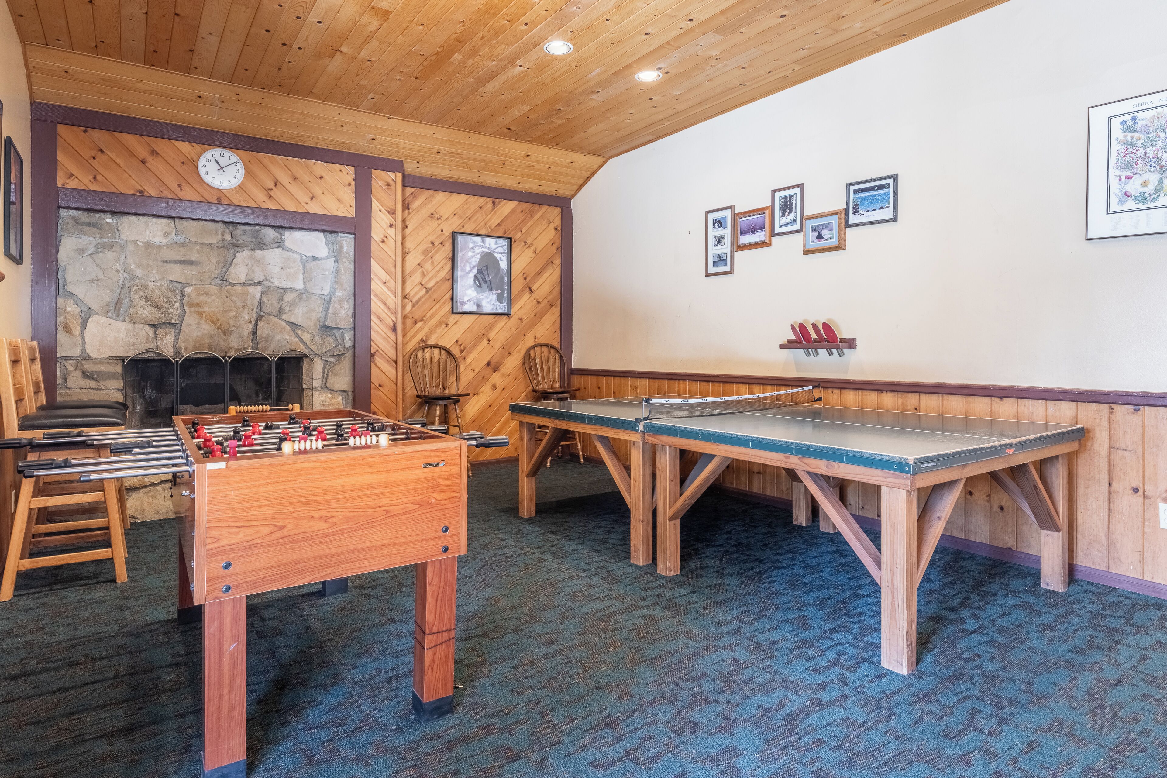 Une pièce chaleureuse avec une table de baby-foot, une table de ping-pong et une cheminée en pierre.