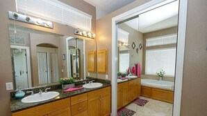 A bathroom with two sinks, a vanity, a bathtub, and a shower area. - Spacious 5-bedroom house in delightful Elk Grove with AC, WiFi,fitness equipment (elk grove)