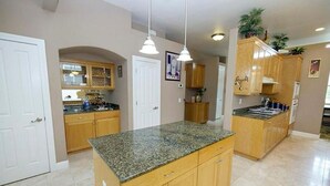 A spacious kitchen with granite countertops, wooden cabinets, and pendant lighting. - Spacious 5-bedroom house in delightful Elk Grove with AC, WiFi,fitness equipment (elk grove)