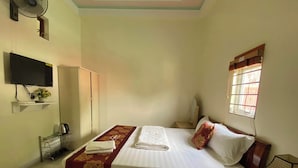 A hotel room with a bed, a TV mounted on the wall, a window with blinds, a fan, and a small table with a lamp. - Sky Hotel Moc Chau - by BAY LUXURY (Moc Son)