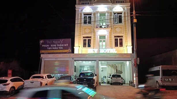 A hotel with a well-lit entrance and multiple cars parked in front. - Sky Hotel Moc Chau - by BAY LUXURY (Moc Son)