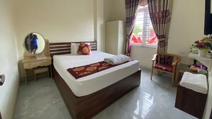 A hotel room with a large bed, a wooden nightstand, a mirror, a chair, a desk, and a window with curtains. - Sky Hotel Moc Chau - by BAY LUXURY (Moc Son)