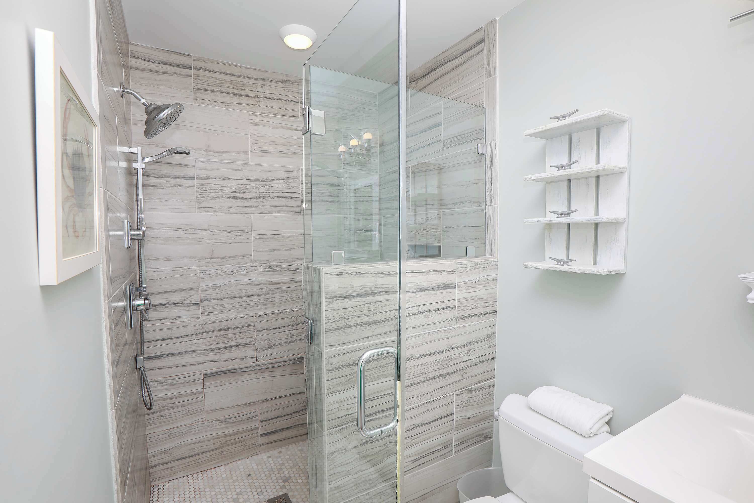 Une salle de bain moderne avec une douche à parois de verre, des toilettes blanches et un lavabo blanc.