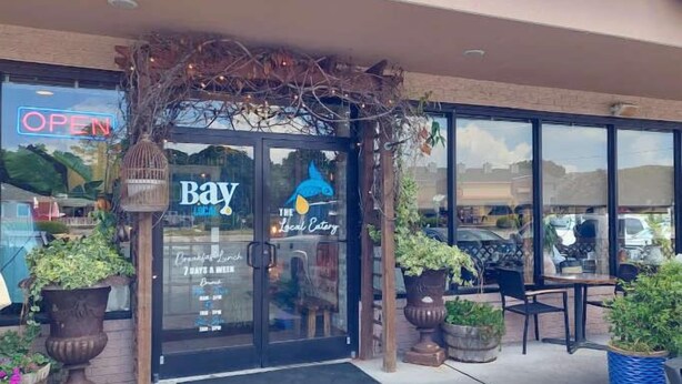 A restaurant entrance with a 'Bay Local' sign, outdoor seating, and potted plants. - Sojourn's Sea Views with Balcony Sleeps 4 (Virginia Beach)