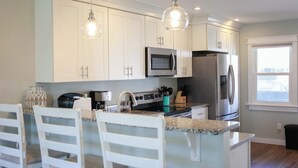 A modern kitchen with white cabinets, stainless steel appliances, and a granite countertop. - Sojourn's Sea Views with Balcony Sleeps 4 (Virginia Beach)