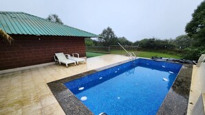 Una piscina rettangolare con una scaletta in metallo, circondata da un solarium piastrellato.